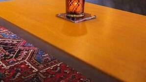 A room with a sofa, a table with a candle, and a patterned rug.
