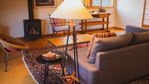 A cozy living room with a sofa, a lamp, a chair, a small table with a tray, and a fireplace.