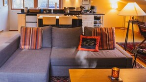 A modern living room with a sofa, pillows, a coffee table, and a lamp.