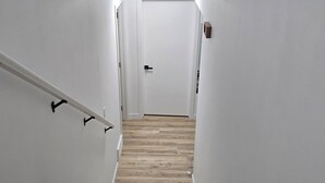 Una escalera de madera con paredes blancas y una puerta blanca al final.