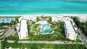 Ein Resort mit mehreren weißen Gebäuden, einem zentralen Pool und Blick auf den Strand.