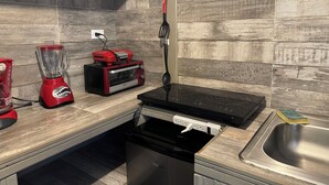 Een keuken met een inbouwoven, een broodrooster, een blender, een vaatwasser en een spoelbak.