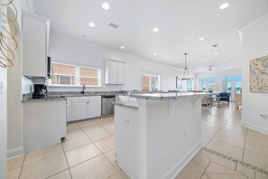 Una cocina amplia con muebles blancos, una isla grande y un comedor con candelabro.