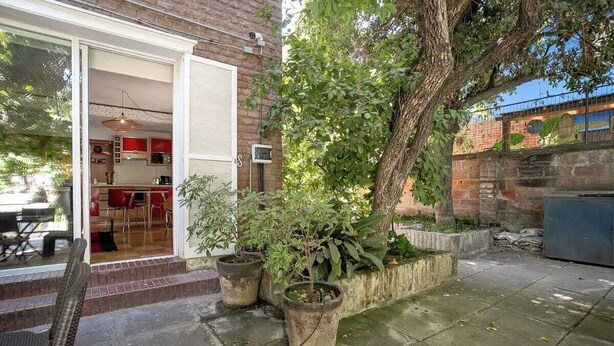 A patio with a dining table and chairs, a brick wall, and potted plants. - Family Time Duplex Family Getaway with Pool (Providencia)