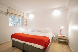 Une chambre à coucher comprenant un lit, une table de chevet, une fenêtre avec des stores et un ventilateur de plafond.