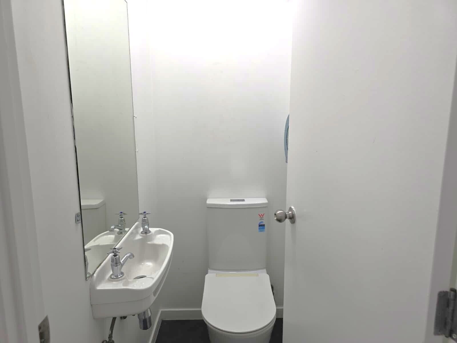 Un bany petit i blanc amb un lavabo i un vàter.