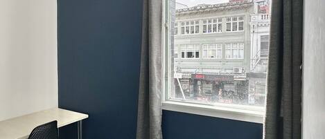 A room with a large window, a desk, and a chair.