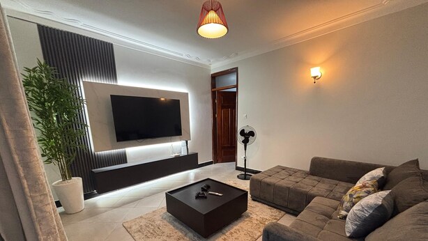 A modern living room with a flat-screen TV, a dark coffee table, and a grey sofa. - Sky View 1-bedroom apartment in the heart of Kampala (Kampala)