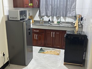 A compact kitchen with a refrigerator, microwave, sink, and a small black appliance. - Sky View 1-bedroom apartment in the heart of Kampala (Kampala)