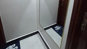 A bathroom with a large mirror, white walls, a door, and a blue and white patterned floor. - Sky View 1-bedroom apartment in the heart of Kampala (Kampala)