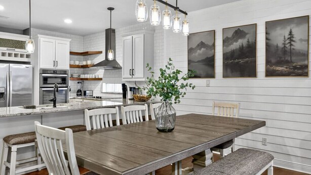 A modern kitchen with white cabinetry, stainless steel appliances, and a wooden dining table with chairs. - Conroe 4BR near The Woodlands | Arcade Game Room, Gym, Playground, Sleeps 13 (Conroe)