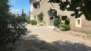 A rustic building with a gravel driveway, a small garden, and a clear sky.
