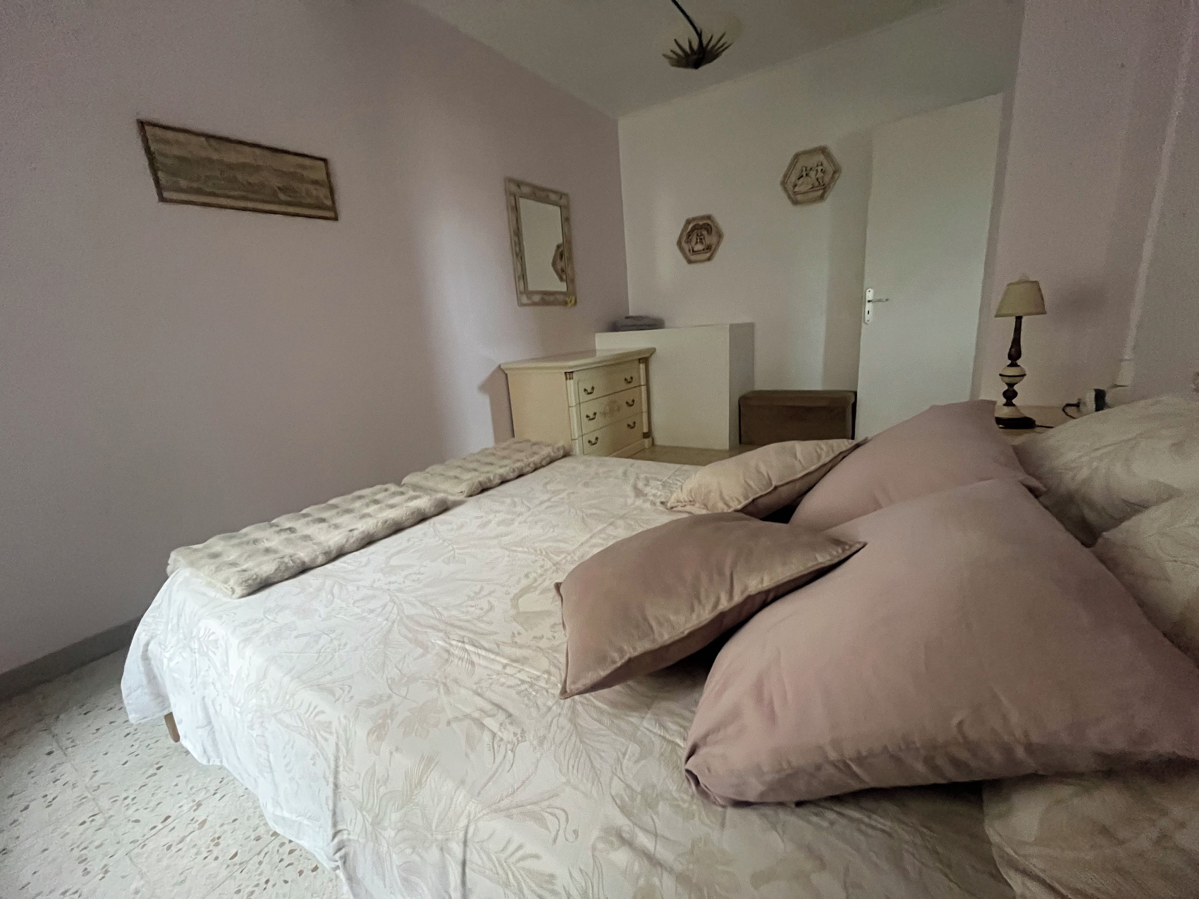 Ein Schlafzimmer mit Bett, Kommode, Spiegel und Lampe.