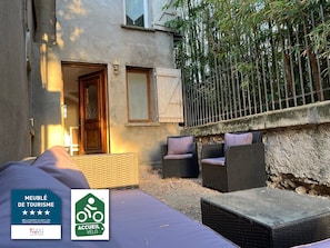 Una habitación de hotel con una cama, un rincón de descanso con muebles de mimbre y vistas a árboles de bambú.