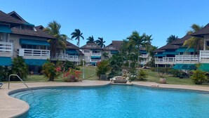 A resort with a central swimming pool, multiple guest villas with balconies, and lush tropical landscaping. - Garden-Sea view, 2 bedroom/2bath Montego Freeport (Montego Bay)