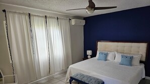 A bedroom with a bed, a nightstand, a ceiling fan, and a window with curtains. - Garden-Sea view, 2 bedroom/2bath Montego Freeport (Montego Bay)