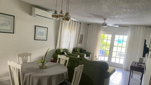A dining area with a table and chairs, a green sofa, and a ceiling fan. - Garden-Sea view, 2 bedroom/2bath Montego Freeport (Montego Bay)