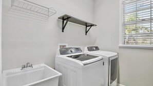 A laundry room with a washing machine, dryer, and sink. - New! Gorgeous home on AMI. Heated pool! (Anna Maria)