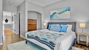 A bedroom with a bed, a nightstand, a dresser, and a painting on the wall. - New! Gorgeous home on AMI. Heated pool! (Anna Maria)