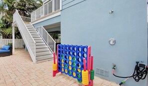 Ein Wohnbereich im Freien mit einer Treppe, einem bunten Gesellschaftsspiel und einem Gartenschlauch.