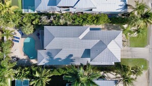 An aerial view of a property with a swimming pool, multiple buildings, and palm trees. - New! Gorgeous home on AMI. Heated pool! (Anna Maria)