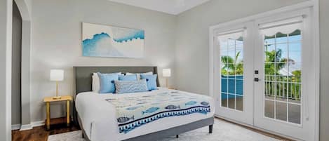 A bedroom with a bed, a nightstand, a ceiling fan, a painting, and a view through a sliding door.
