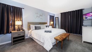 Habitación de hotel ordenada con cama, mesitas de noche, televisor y escritorio.