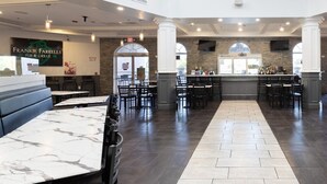 Un restaurante espacioso con mesas de mármol y piso oscuro, que incluye una zona de bar y un cartel que dice 'Frankie Farrells Pub & Grille'.