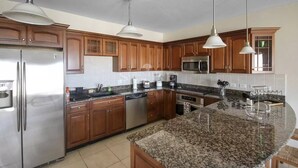 Una cocina moderna con armarios de madera, electrodomésticos de acero inoxidable y una isla de granito.