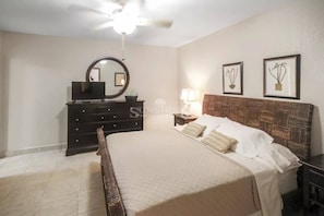 A bedroom with a bed, dresser, mirror, and wall-mounted lights. - Caribbean Getaway: 2BR Condo at Rainbow Beach Club (Cupecoy)