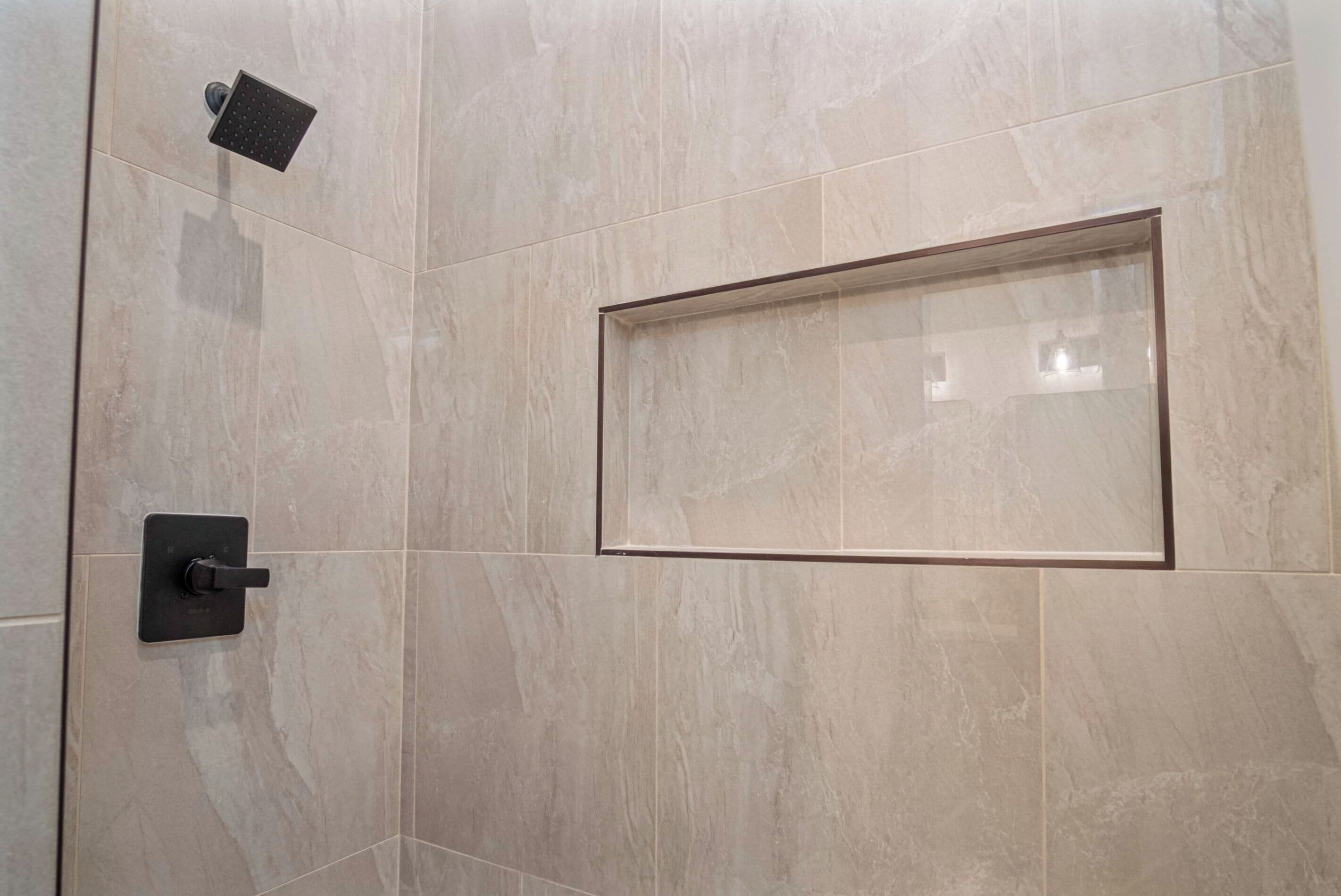 Zona de ducha con cabina de vidrio rectangular y ducha de mano.