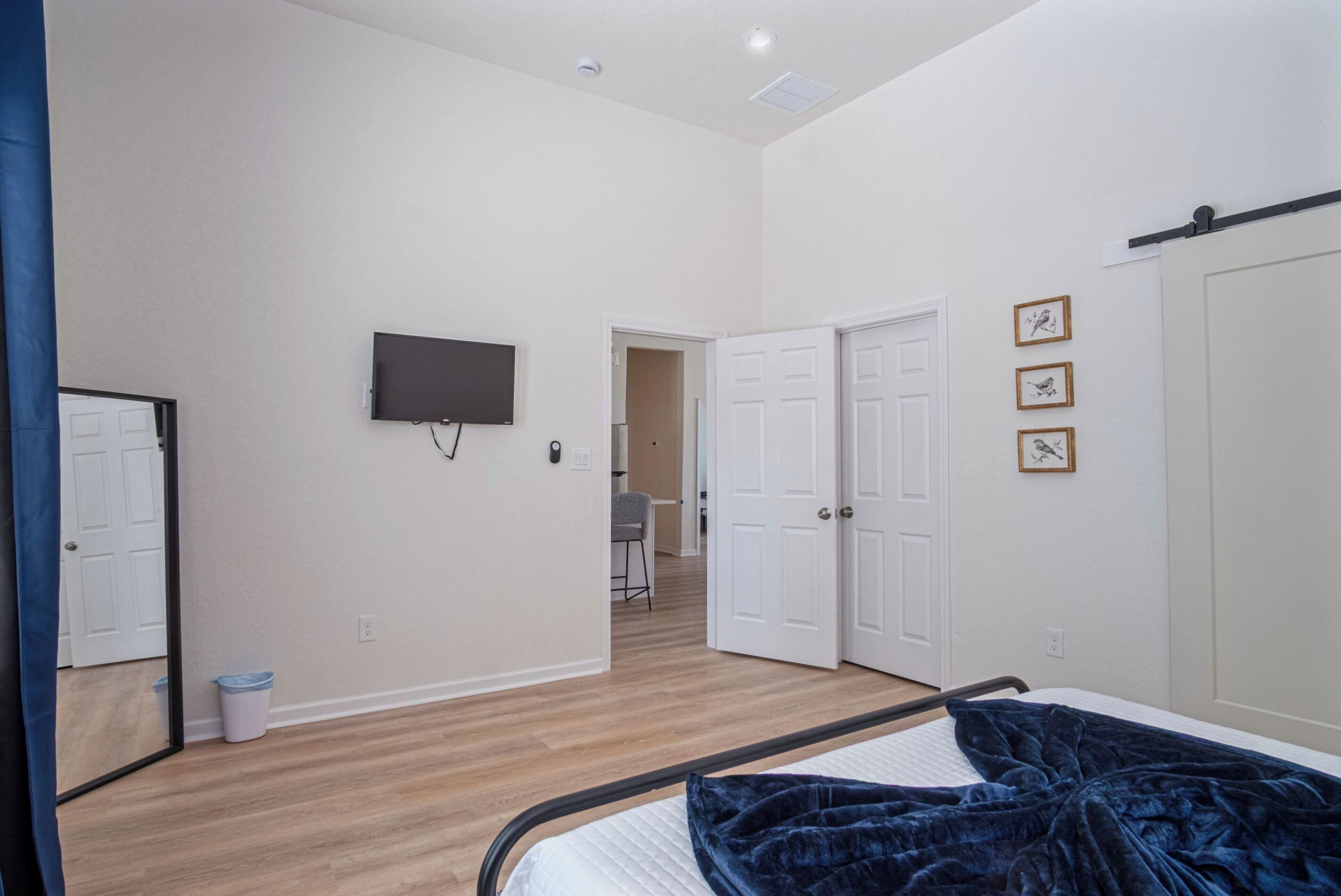Un dormitorio con una cama, un televisor y una puerta que da a otra habitación.