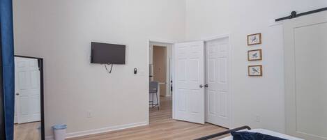 Un dormitorio con una cama, un televisor y una puerta que da a otra habitación.