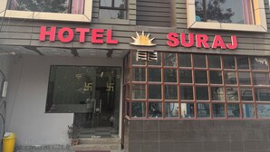Een meerlaags gebouw met een bord met daarop 'HOTEL SURAJ' boven de ingang.