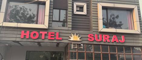 Un edificio de varios pisos con un letrero que dice "HOTEL SURAJ" sobre la entrada.