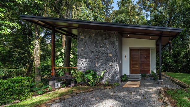 Una casa moderna con fachada de piedra, puerta de madera y un porche cubierto.