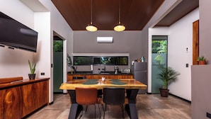 Una cocina moderna con una mesa de comedor de madera, dos sillas y un televisor integrado.