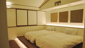 Een slaapkamer met twee bedden, houten vloeren en een schuin dak.