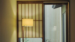 Een kamer met een bank, een tafeltje, een lamp en een schuifdeur naar een tuin.