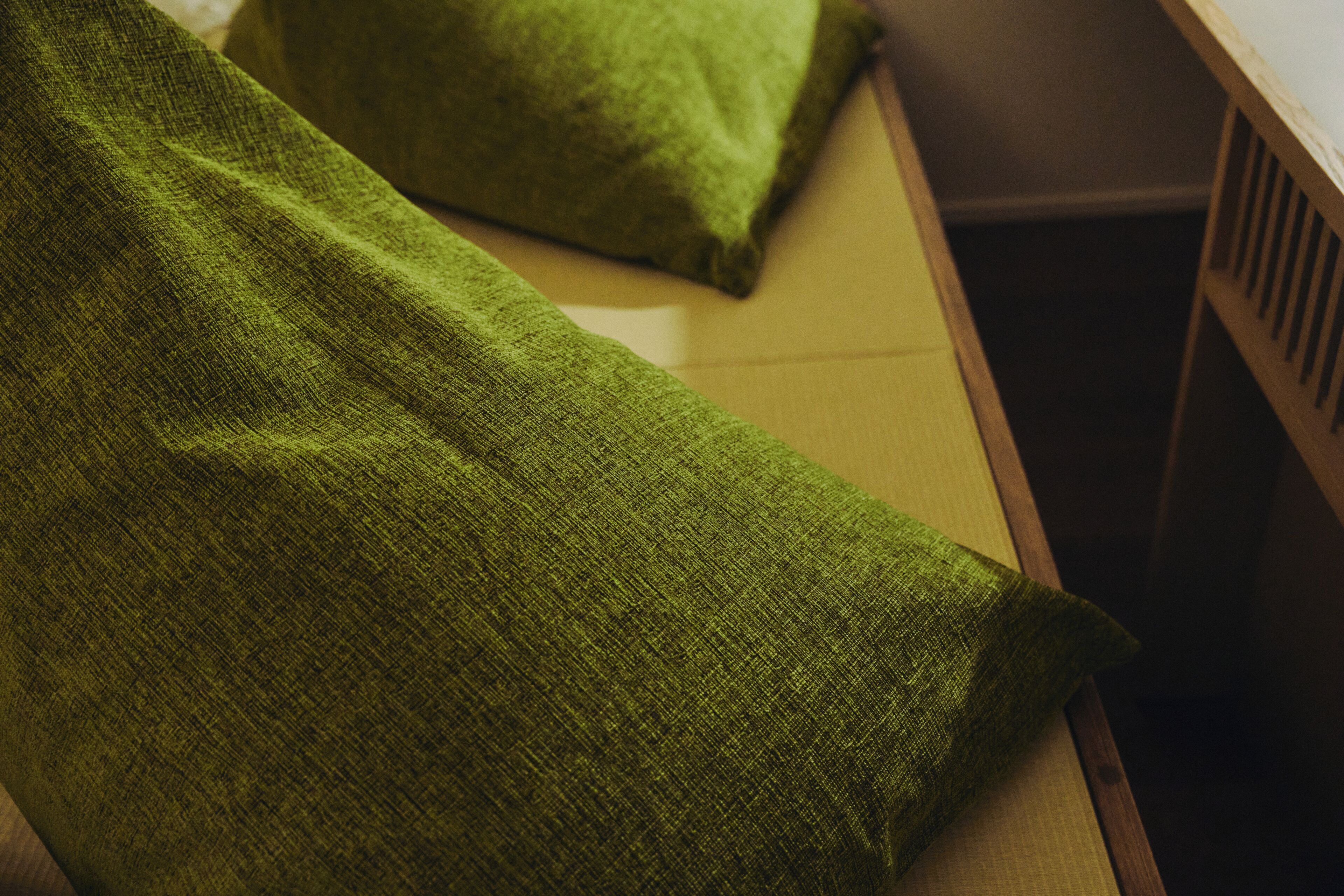 A green fabric draped over a wooden surface, possibly a bed or couch.
