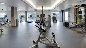 Une salle de sport moderne dotée de divers équipements d’exercice, de grandes fenêtres et d’un aménagement spacieux.
