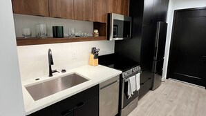 Une cuisine moderne avec des meubles en bois foncé, des appareils électroménagers en acier inoxydable et un plan de travail blanc.
