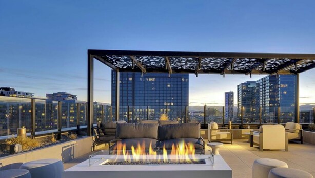 Une terrasse sur le toit dotée d’un foyer, d’un espace salon et offrant une vue sur la ville.