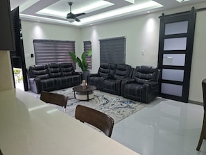 Ein modernes Wohnzimmer mit einer Sofagarnitur, einem Couchtisch und einem Essbereich mit Tisch und Stühlen.