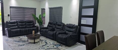 A modern living room with a sofa set, a coffee table, and a dining table with chairs.