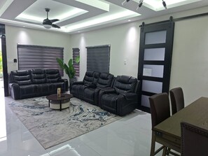 A modern living room with a sofa set, a coffee table, and a dining table with chairs. - Serenity at Paradisiac with a Private Beach (Richmond)