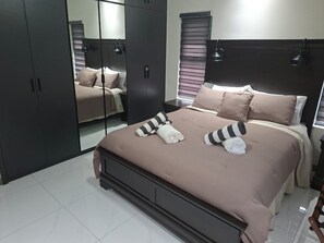 A bedroom with a bed, a wardrobe, and a mirror. - Serenity at Paradisiac with a Private Beach (Richmond)