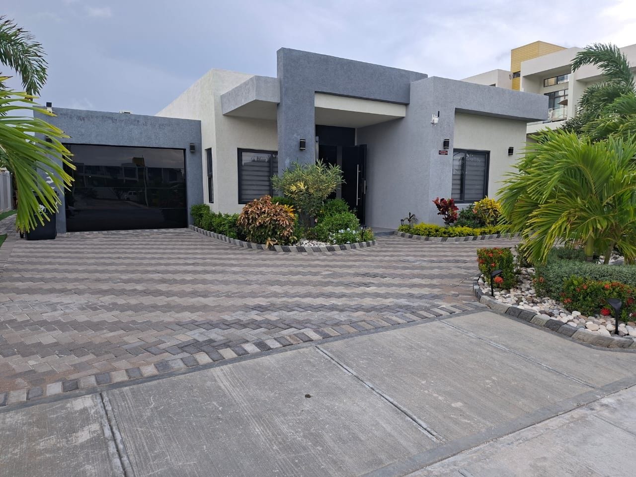 A modern building with a paved driveway, a garage, and landscaped gardens.