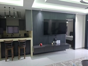 Eine moderne Küche mit integriertem Fernseher, Barhocker und einem großen Fenster.
