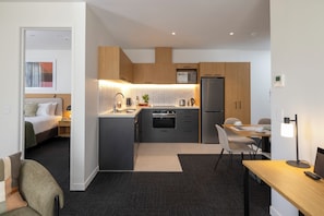 Una habitación de hotel moderna con kitchenette, zona de comedor y un dormitorio independiente.